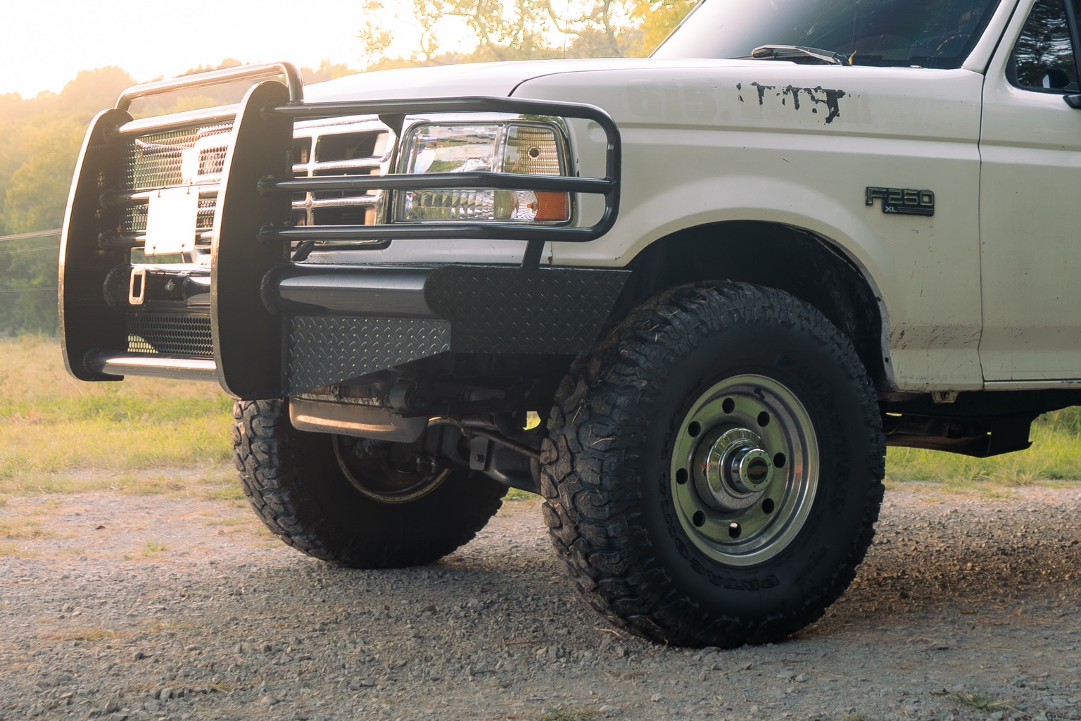 Front wheel and grille of a white Ford truck