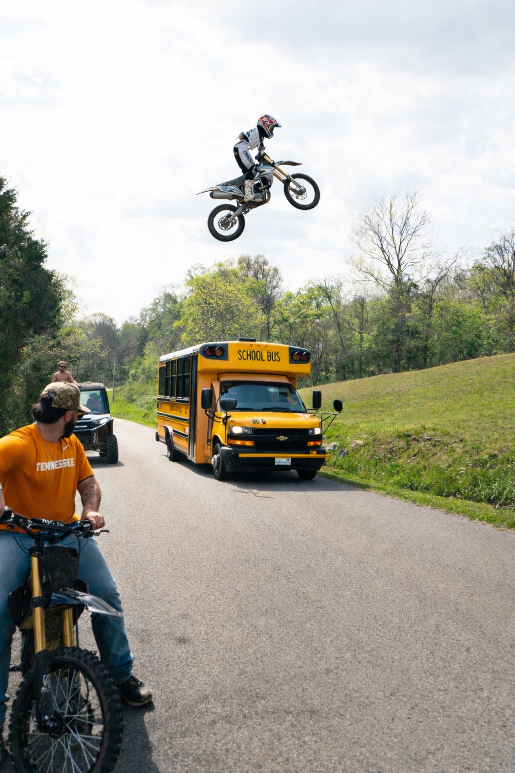Dirt-bike rider jumping beside a school bus